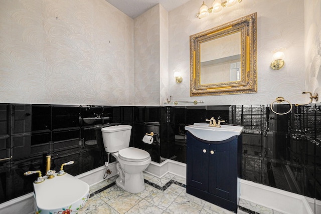bathroom featuring vanity, toilet, wallpapered walls, and marble finish floor