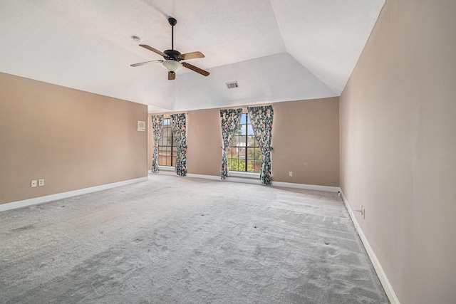 carpeted spare room featuring baseboards, ceiling fan, lofted ceiling, and visible vents