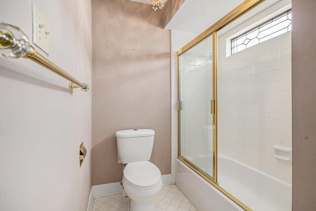 bathroom featuring tile patterned flooring, baseboards, combined bath / shower with glass door, and toilet