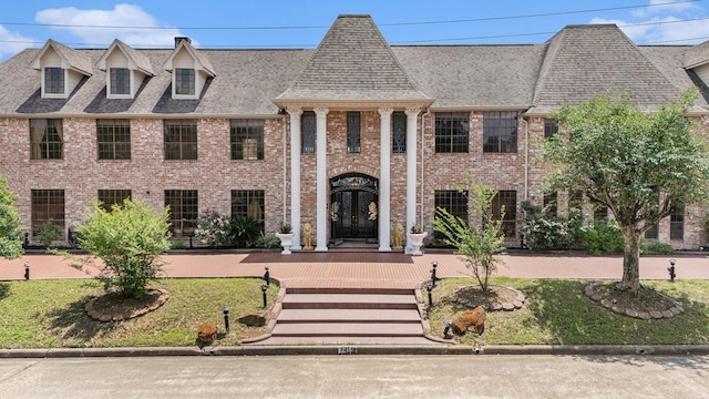 neoclassical / greek revival house featuring french doors, brick siding, a shingled roof, and a front yard