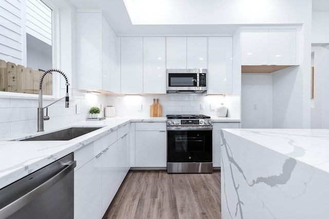 3515 Mcilhenny St, Houston, TX 77004 - kitchen with modern cabinets, light wood-type flooring, white cabinets, a sink, and stainless steel appliances