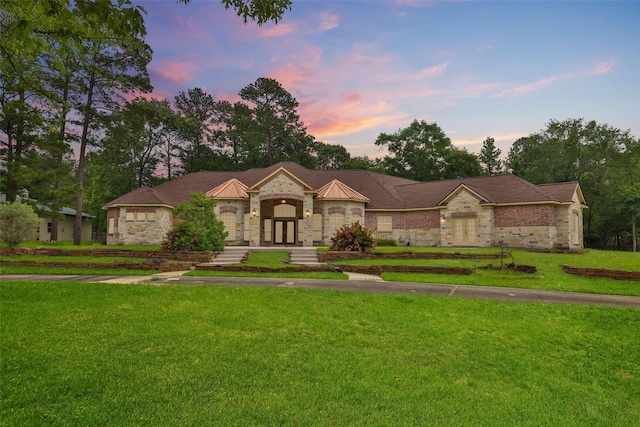view of front facade featuring a yard, a standing seam roof, and stone siding