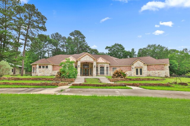 view of front facade with a front lawn, french doors, and stone siding
