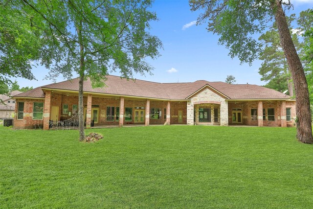 back of property with french doors, a yard, and brick siding