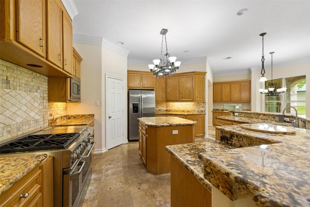 kitchen with a kitchen island, appliances with stainless steel finishes, brown cabinetry, and an inviting chandelier