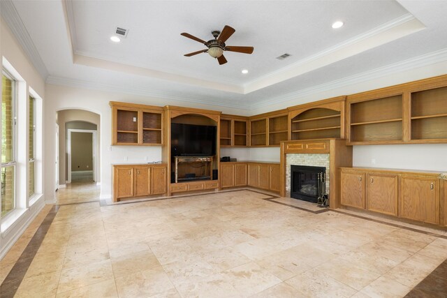 unfurnished living room featuring arched walkways, ceiling fan, and a raised ceiling