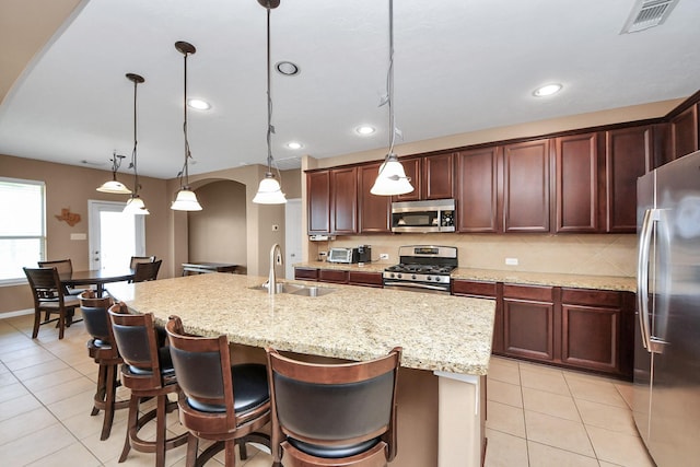 7603 Chimney Gap, Missouri City, TX 77459 - kitchen featuring visible vents, arched walkways, a sink, stainless steel appliances, and light tile patterned flooring