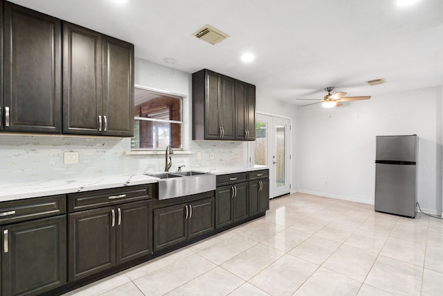 kitchen featuring visible vents, freestanding refrigerator, a ceiling fan, tasteful backsplash, and a sink