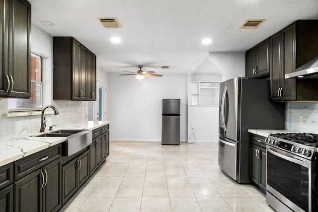 kitchen with ceiling fan, a sink, stainless steel appliances, baseboards, and backsplash