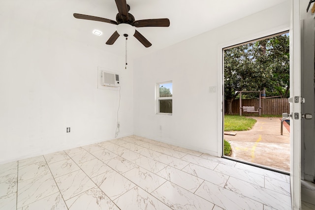 spare room with a wall mounted air conditioner, marble finish floor, a ceiling fan, and a healthy amount of sunlight