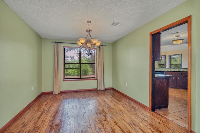 7739 County Road 684, Sweeny, TX 77480 - unfurnished dining area with an inviting chandelier, a textured ceiling, wood finished floors, and visible vents