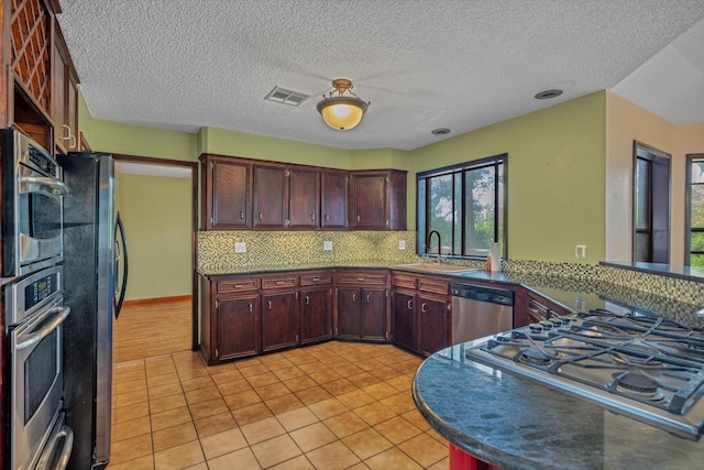 7739 County Road 684, Sweeny, TX 77480 - kitchen with visible vents, decorative backsplash, a sink, light tile patterned floors, and stainless steel appliances