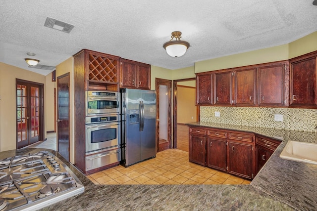 7739 County Road 684, Sweeny, TX 77480 - kitchen featuring visible vents, reddish brown cabinets, light tile patterned floors, appliances with stainless steel finishes, and a warming drawer