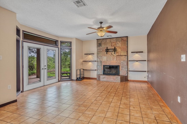 7739 County Road 684, Sweeny, TX 77480 - unfurnished living room with a textured ceiling, a tiled fireplace, ceiling fan, french doors, and tile patterned floors