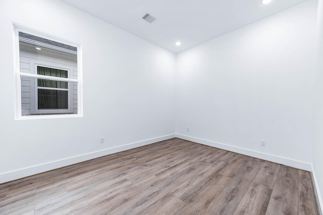 unfurnished room with baseboards, recessed lighting, wood finished floors, and visible vents