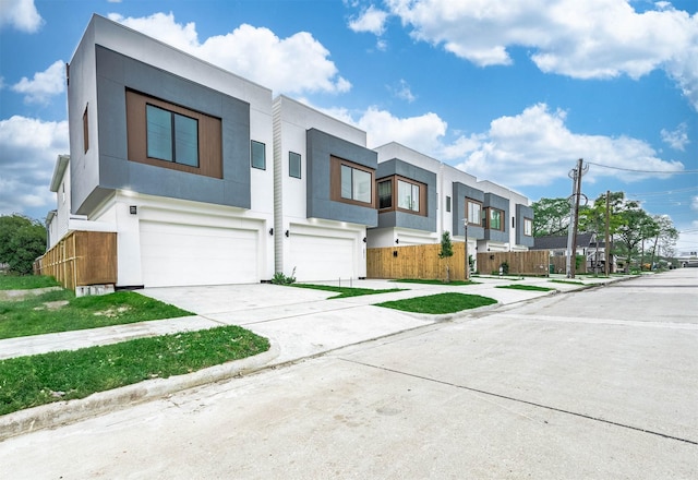 contemporary home with a garage, stucco siding, a residential view, and concrete driveway