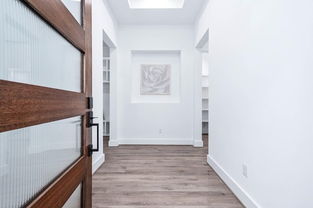 corridor with baseboards and wood finished floors