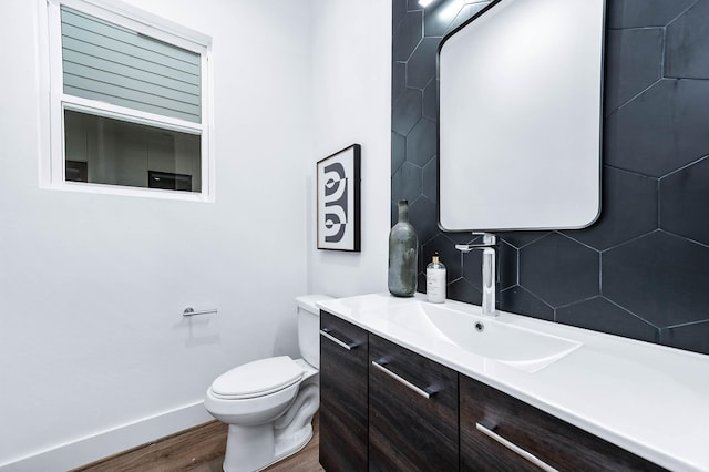 bathroom featuring vanity, decorative backsplash, wood finished floors, toilet, and baseboards