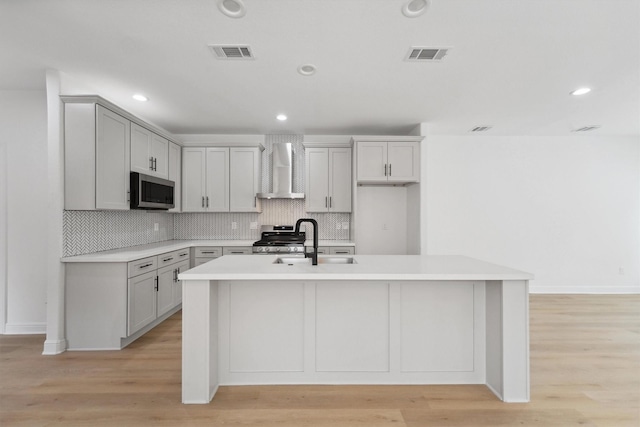 5013 Golden Forest Dr, Houston, TX 77091 - kitchen with wall chimney range hood, stainless steel appliances, a sink, tasteful backsplash, and an island with sink