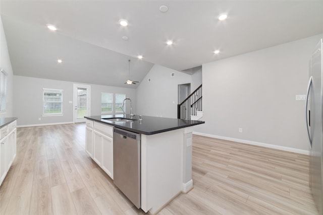 kitchen with appliances with stainless steel finishes, dark countertops, vaulted ceiling, light wood-type flooring, and a sink