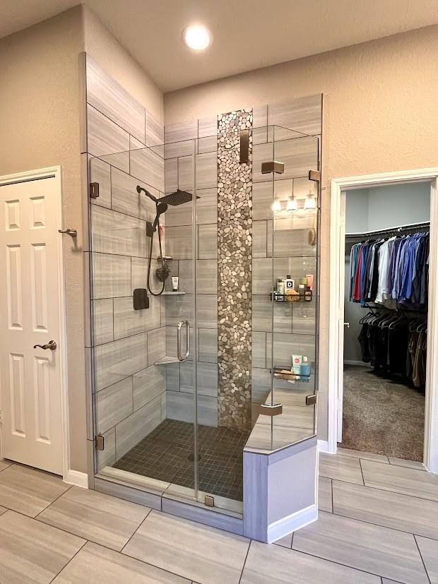 bathroom featuring recessed lighting, baseboards, a spacious closet, and a stall shower