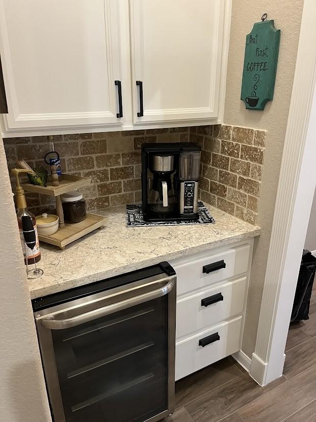 interior details featuring wine cooler, decorative backsplash, and white cabinetry