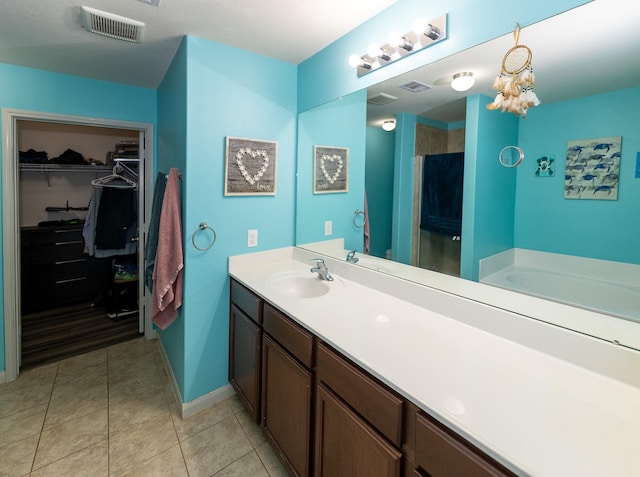 full bathroom with visible vents, tile patterned flooring, a stall shower, vanity, and a spacious closet