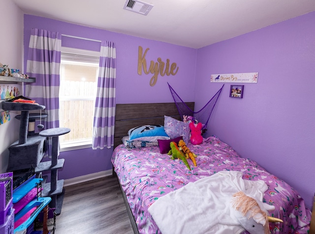 bedroom with baseboards, wood finished floors, and visible vents