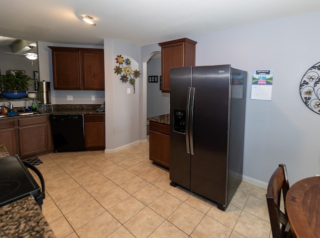 kitchen featuring a sink, baseboards, arched walkways, light tile patterned floors, and black appliances