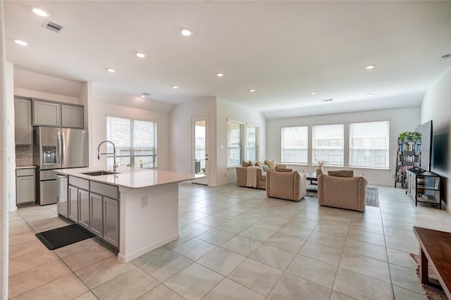 kitchen with stainless steel fridge, a sink, gray cabinets, light tile patterned floors, and visible vents