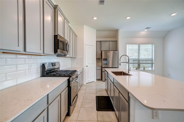kitchen featuring a sink, gray cabinets, stainless steel appliances, light tile patterned floors, and tasteful backsplash