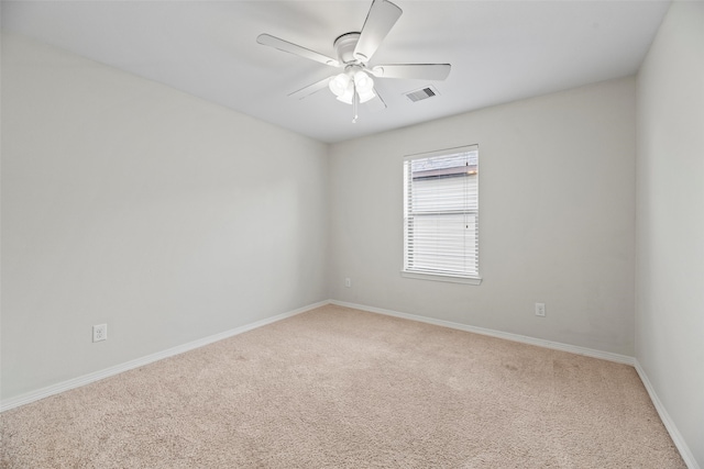 carpeted spare room featuring visible vents, a ceiling fan, and baseboards