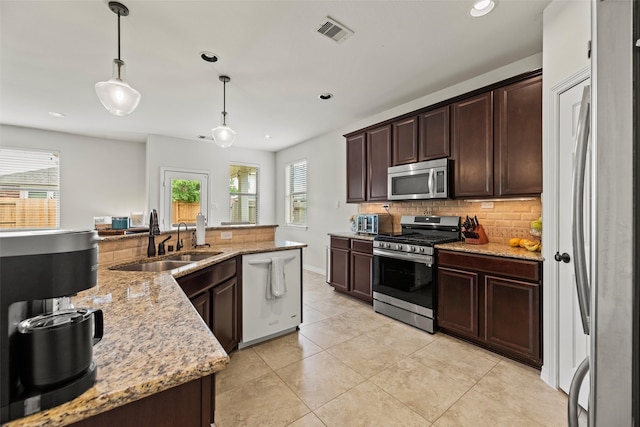 kitchen featuring dark brown cabinets, a sink, stainless steel appliances, backsplash, and visible vents