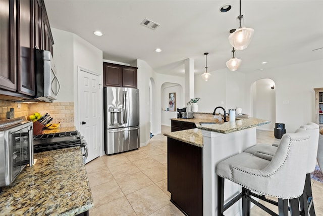 kitchen featuring visible vents, arched walkways, a sink, and appliances with stainless steel finishes