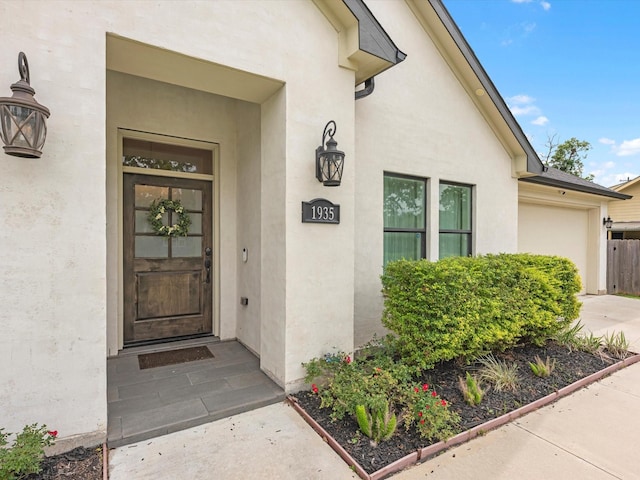 entrance to property with an attached garage and stucco siding
