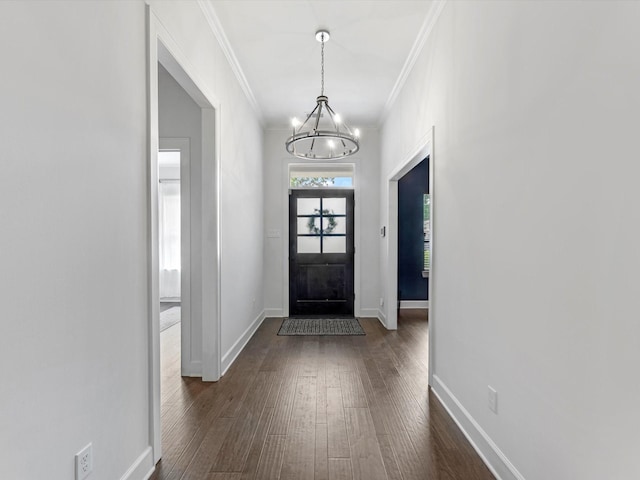 foyer entrance featuring dark wood-type flooring, ornamental molding, baseboards, and a chandelier