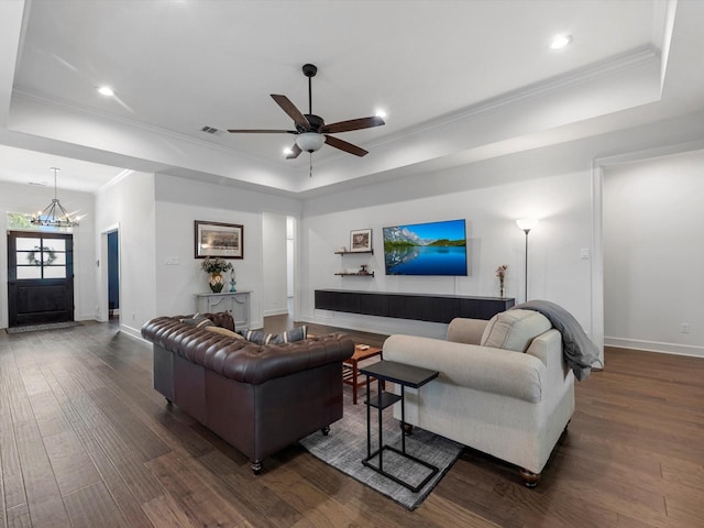 living area featuring dark wood-style flooring, a raised ceiling, ceiling fan with notable chandelier, baseboards, and visible vents