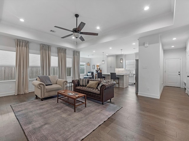 living area with dark wood-style flooring, ceiling fan, a raised ceiling, recessed lighting, and visible vents