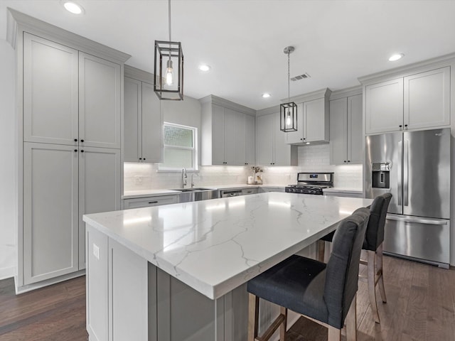 kitchen with dark wood-style flooring, stainless steel appliances, decorative backsplash, and a center island