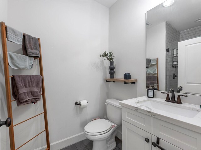 full bath featuring a tile shower, vanity, tile patterned floors, baseboards, and toilet