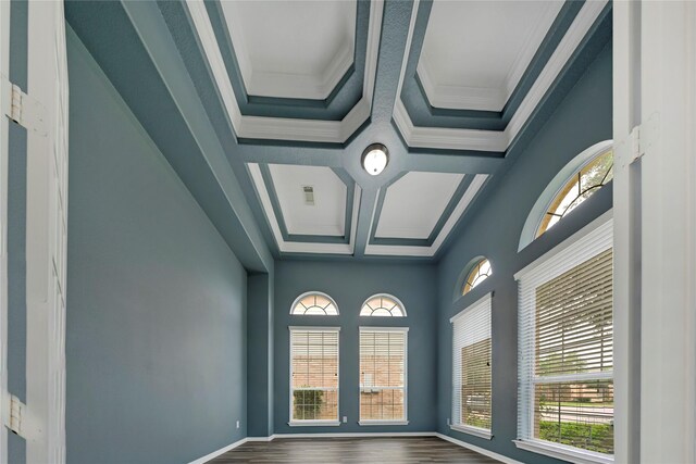 interior space with wood finished floors, baseboards, beamed ceiling, ornamental molding, and coffered ceiling
