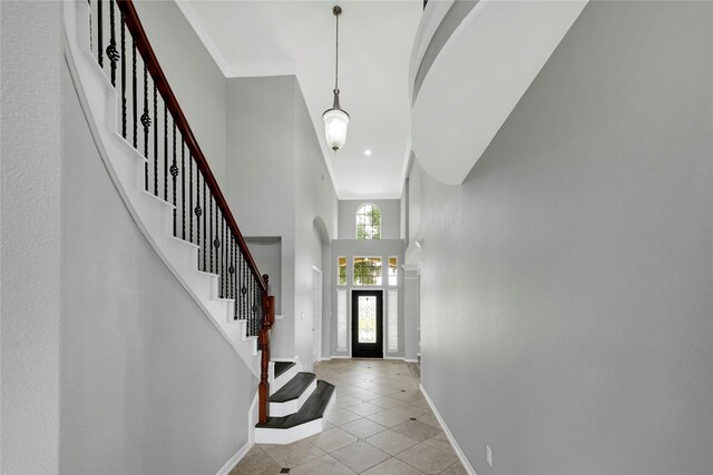 entryway featuring baseboards, a high ceiling, light tile patterned floors, and stairway