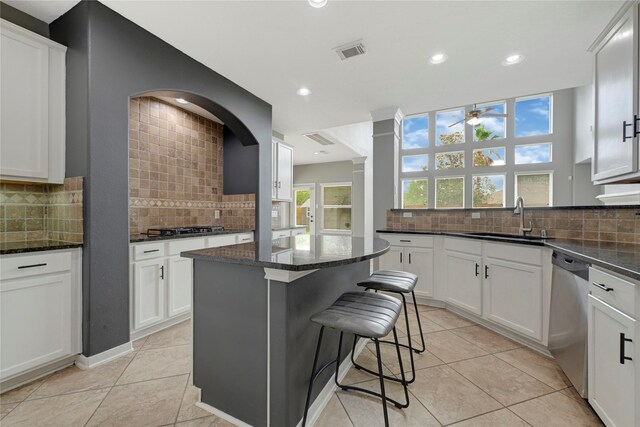 kitchen featuring a sink, tasteful backsplash, stainless steel dishwasher, and visible vents
