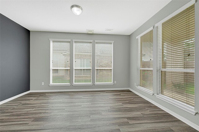 empty room with baseboards, visible vents, and wood finished floors