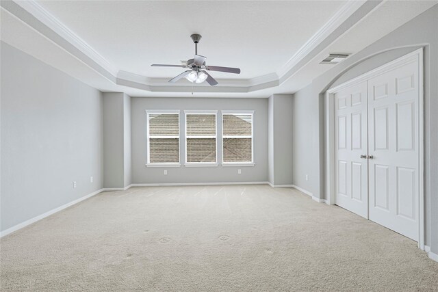 unfurnished bedroom featuring crown molding, visible vents, light colored carpet, and a raised ceiling