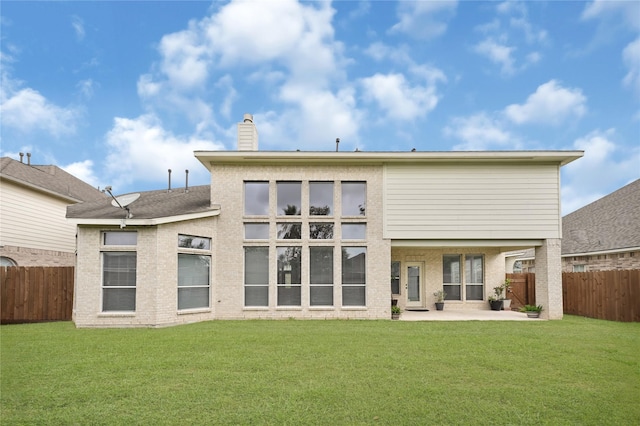 rear view of property with a lawn, a fenced backyard, a patio area, and a chimney