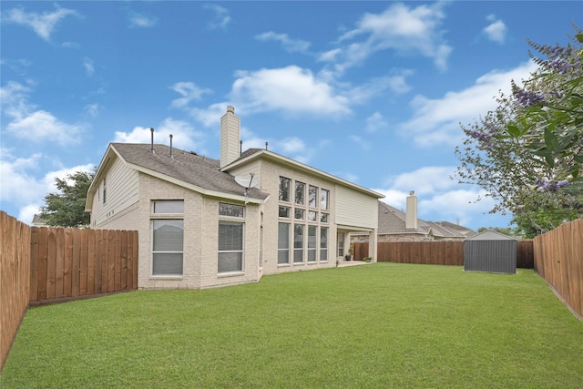 rear view of house featuring a chimney, an outbuilding, a fenced backyard, a shed, and a yard
