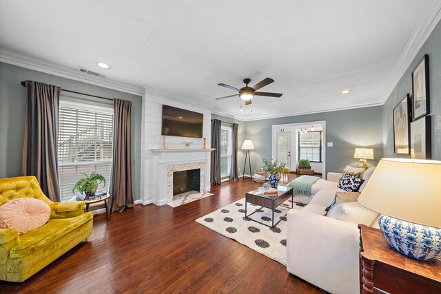 living area with crown molding, ceiling fan, visible vents, and wood finished floors