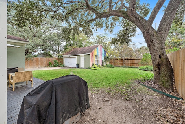 view of yard featuring a detached garage, a deck, an outdoor structure, and a fenced backyard