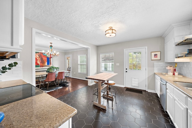 kitchen with light countertops, dark tile patterned flooring, white cabinets, and dishwasher